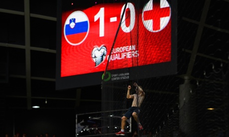 A fan climbs the netting under the scoreboard.