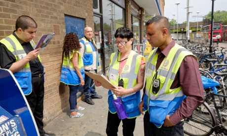 Supervisors Mohammed Haque (right) and Tracey Grant (2nd right) discuss  break times as fellow Business and Community Wardens wait in Finsbury Park, London on Friday, June 12, 2015.  The government's community work placement is intended to give long time unemployed people work experience. However, they say they are standing around for 30 hours a week and get no experience, cannot pay for food and receive no help with applying for jobs.Photograph:    Frantzesco Kangaris