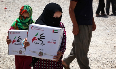 Displaced Iraqis, who fled due to the ongoing conflict between pro-government forces and Islamic State (IS) group jihadists, carry food aid distributed by the United Arab Emirate's Red Crescent at the Bahrka refugee camp, where they're taking shelter, ten kilometres west of Arbil, the capital of the Kurdish autonomous region in northern Iraq, on June 6, 2015. The International Monetary Fund said it was preparing 833 million US dollars in emergency financial assistance to Iraq as the country battles the Islamic State insurgency.