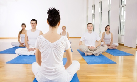 Group of people in lotus pose at a yoga class