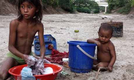 Esteffany Epieyu, 11, and her nephew Luis Miguel wash clothes in the dry riverbed.