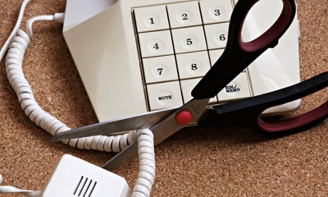 A pair of scissors cutting through a telephone cord