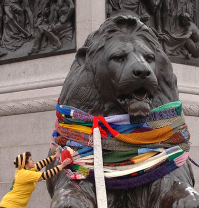 A member of the 'Stitch and Bitch' knitting group wraps giant colourful scarves around the Trafalger Square lions in London.