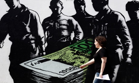 Pedestrian passes a graffiti artwork titled Death of euros, painted by French street artist Goin, on a wall in Athens, Greece.