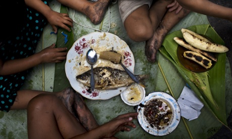 In this April 20, 2015 photo, siblings Piero, Ariana and Priscila eat a lunch of fish, bananas and rice as their parents sell fish at a street market in Belen, a neighborhood nicknamed  Venice of the Jungle  in Iquitos, Peru. According to official statistics, 40 percent of the children in Belen suffer from malnutrition and 66 percent of the entire population is poor.