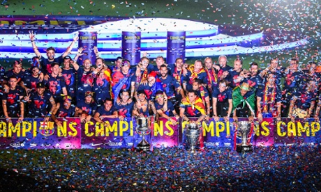 Barcelona players celebrate with La Liga, Copa del Rey and Champions League trophies.