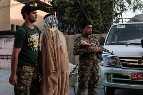 Security officers from a Shia militia frisk people entering a memorial for a military leader.