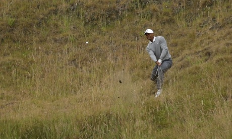 Tiger Woods hits out of the tall grass on his first hole, the 10th.