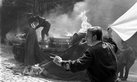 A youngster carrying a Czechoslovak flag runs past a burning Soviet tank set afire by Prague residents in  Prague on 21 August 1968 as the Soviet-led invasion by the Warsaw Pact armies crushed the so called Prague Spring reform in former Czechoslovakia.        (Photo credit should read STF/AFP/Getty Images)TANK|WARANDCONFLICT|HISTORY|WARSAWPACT.