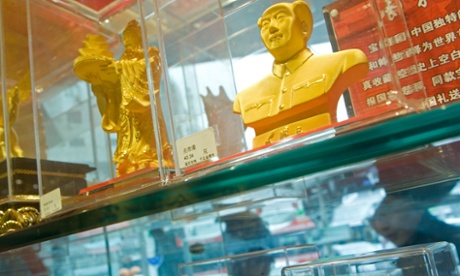 Pedestrians walk past gold products at a department store specializing in precious metals and stones in Beijing