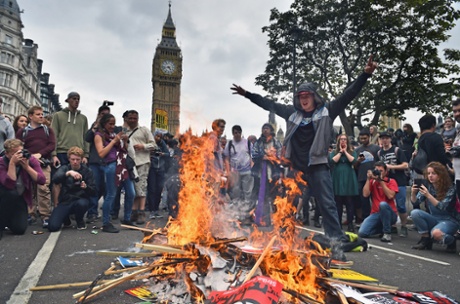 Protesters set fire to placards in central London during a demonstration against austerity and spending cuts.