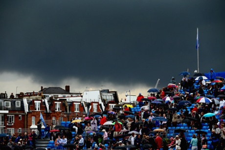 Spectators shelter from the rain as dark clouds loom over centre court.
