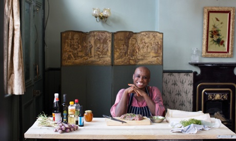 Chef Andi Oliver sits in a kitchen smiling