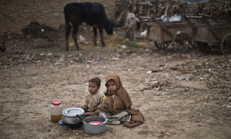 An Afghan refugee boy sits next to a girl selling pans of food in a poor neighbourhood on the outskirts of Islamabad, Pakistan.