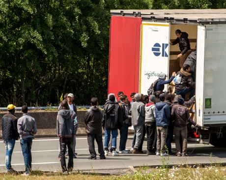 Migrants climb in the back of a lorry on the A16 highway leading to the Eurotunnel in Calais