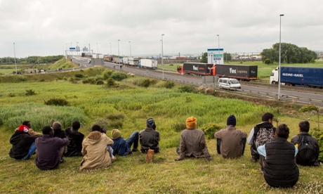 Migrants sit near the A16 as they weigh up which vehicles would be best to try to stowaway on