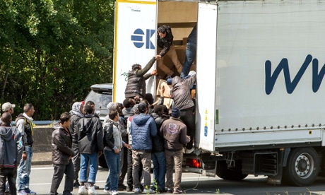 Migrants climb into the back of a lorry in Calais, France
