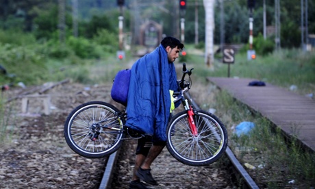 A migrant from Syria carries his bicycle across a railway line in an area of Macedonia near the Greek border.