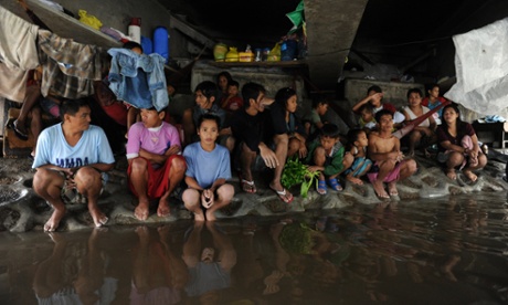 Could a global tax system help stem the rising tide of inequality? A group of Philippine farm workers seek shelter from rains and floodwaters north of Manila, August 2012.