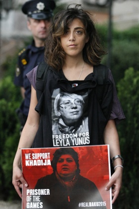 A protester holds a poster showing Azerbaijami jailed journalist Khadija Ismayilova