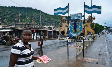 People walk past a city sign in Freetown in August 2014. Sierra Leone has more confirmed cases of Ebola than any other country.