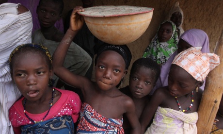 Children shelter from the rain in front of a home in Yangalma village, Nigeria