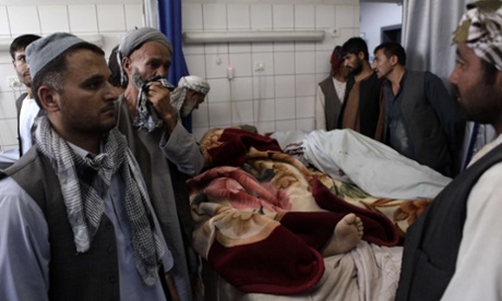 Relatives stand beside the body of an aid worker in Mazar-i-Sharif on June 2, 2015, after he was shot by gunmen in the northern province of Balkh.