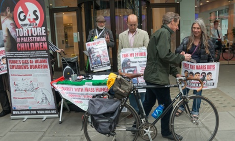 A man takes a leaflet from a protester outside the offices of G4S in May 2014.