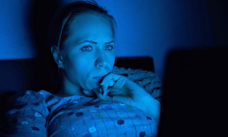 A woman looking at a laptop in bed at night