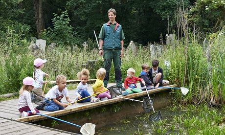 A group of young children searching in water with fishing nets