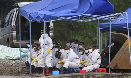 Rescue workers wait to transport bodies to vehicles nearby.