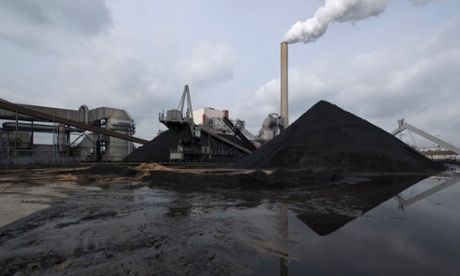 Smoke is emitted from a chimney behind a stack of coal at a RWE AG owned Essent Energie