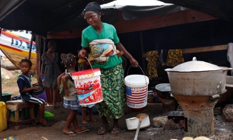 A woman carries buckets at the fishing port of Conakry, Guinea, in November 2014. A new study finds women’s contribution to health and wellbeing of families and communities is undervalued worldwide.