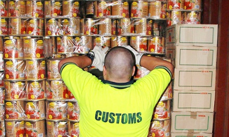A customs official inspects tins of tomato shipped to Australia  that contained 4.4 tonnes of ecstasy tablets.
