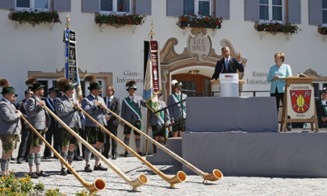 Alpine horn players stand before Barack Obama as he and Angela Merkel speak in the Bavarian village of Krün.