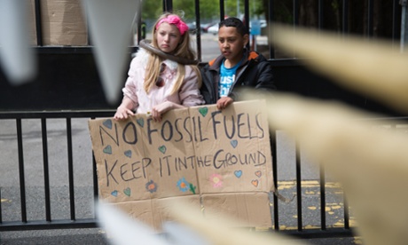 Seen through the teeth of a giant 'Cuadzilla', children stand behind a banner outside the gates of Didcot B power station as part of a protest against the fossil fuel industry by climate action group Reclaim The Power, Appleford, United Kingdom. 1st June 2015.