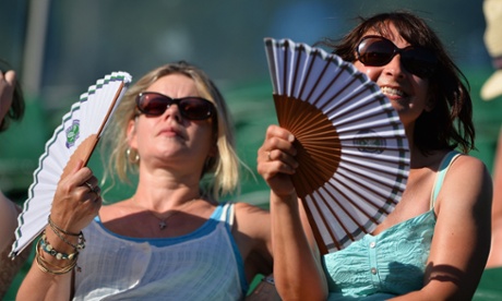 Spectators fan themselves as they watch the action on day two of the 2015 Wimbledon Championships.