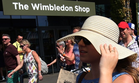 A spectator keeps hold of her sunhat as she enters The All England Tennis Club.