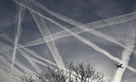 A passenger plane flies through aircraft contrails in the skies near Heathrow Airport