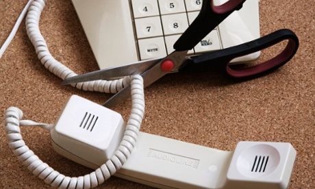 A pair of scissors cutting through a telephone 