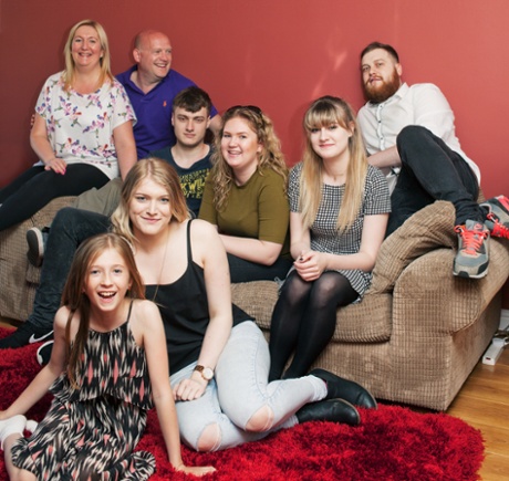 A family of eight sits in their living room