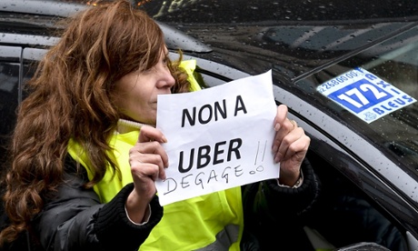 A taxi driver holds a sign reading 'no to Uber, get out!'