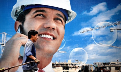 A Chinese worker walks past a billboard along a construction site in Shanghai.