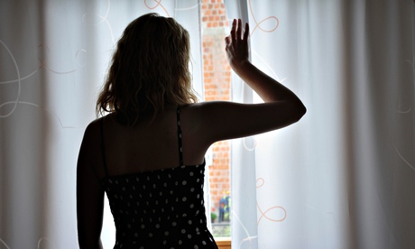 A woman peeking through her curtains