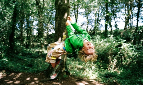 Boy (5-7) swinging on rope hanging from tree in woodland