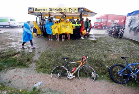 Spectators take shelter from heavy rain and hail as they wait for the riders at the finish line.