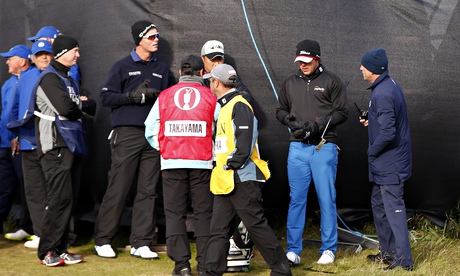 The American Brooks Koepka and others listen to an official during high winds at St Andrews