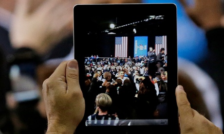 President Barack Obama is seen on a video tablet as he shakes hands after speaking at a campaign event