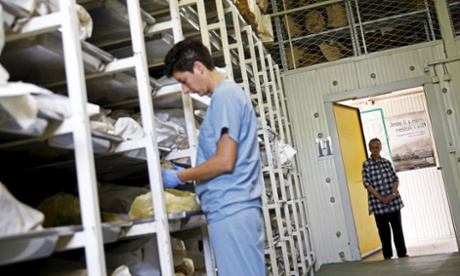 A forensic anthropologist from the International Commission on Missing Persons looks at a skull that Hajra (right) found in the woods.