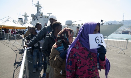 Migrants disembark from an Italian navy vessel after being picked up in the Mediterranean.